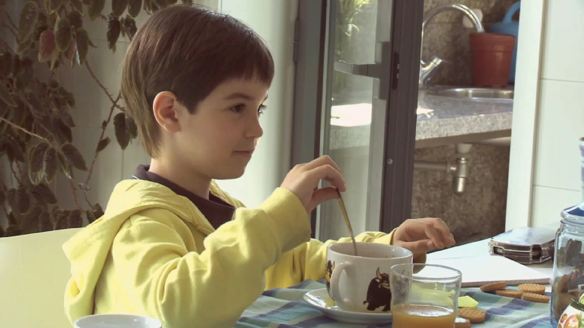 Fotograma de 18 comidas: un neno almorza na mesa da cociña