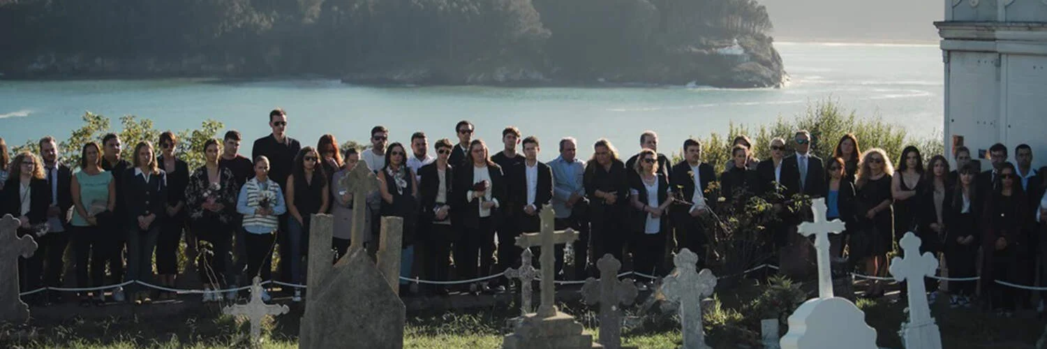 Escena de Rapa: un grupo de persoas nun enterro nun cemiterio fronte ao mar